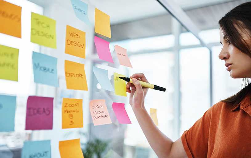 Woman writing marketing ideas on Post-It notes