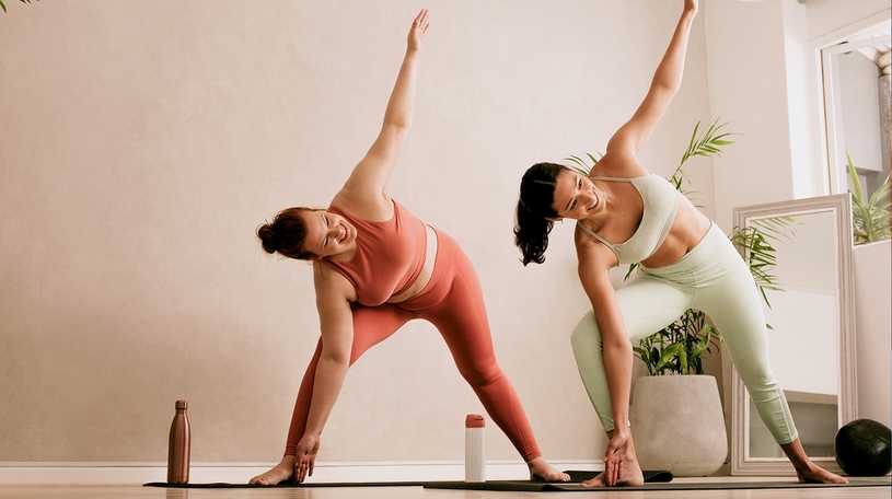 Two women doing yoga poses in their yoga mats