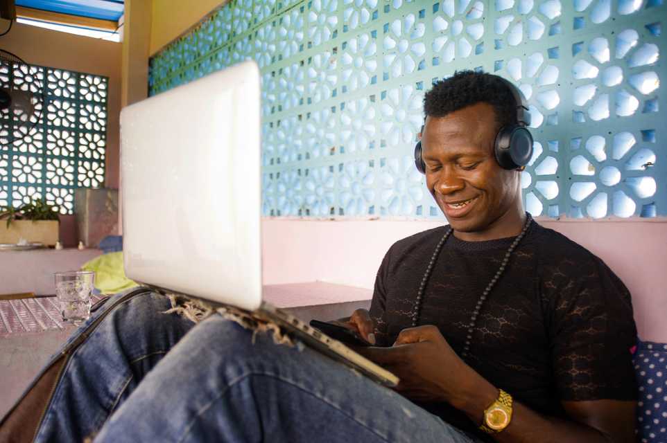 Man smiling with headphones on and using phone