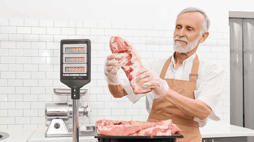 Butcher weighing meat in his shop