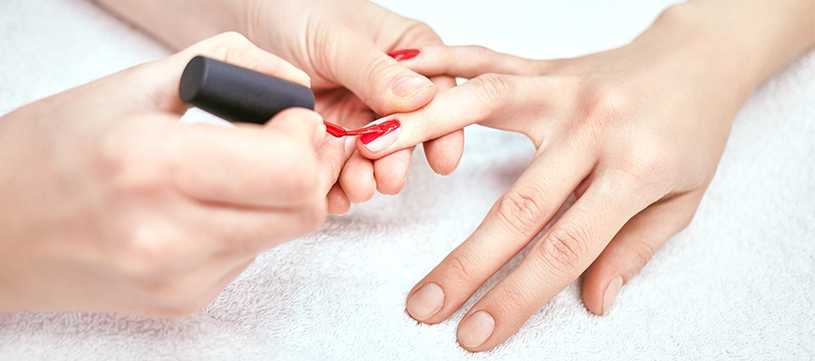 Nail technician painting a clients hands