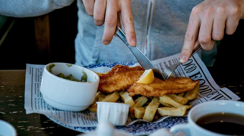 Person eatign fish and chips with a knife and fork