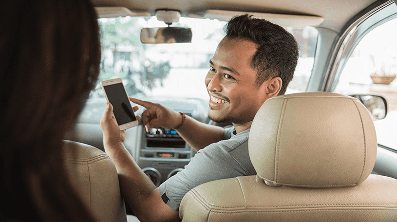 An Uber driver showing a passenger his phone