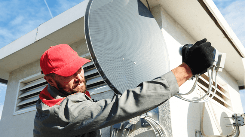 A satellite dish installer fixing a satellite dish