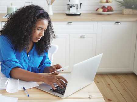 Womanusing laptop and phone to work on taxes