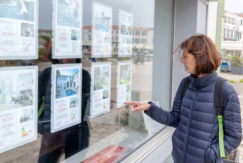 Woman looking at property adverts in estate agent's window