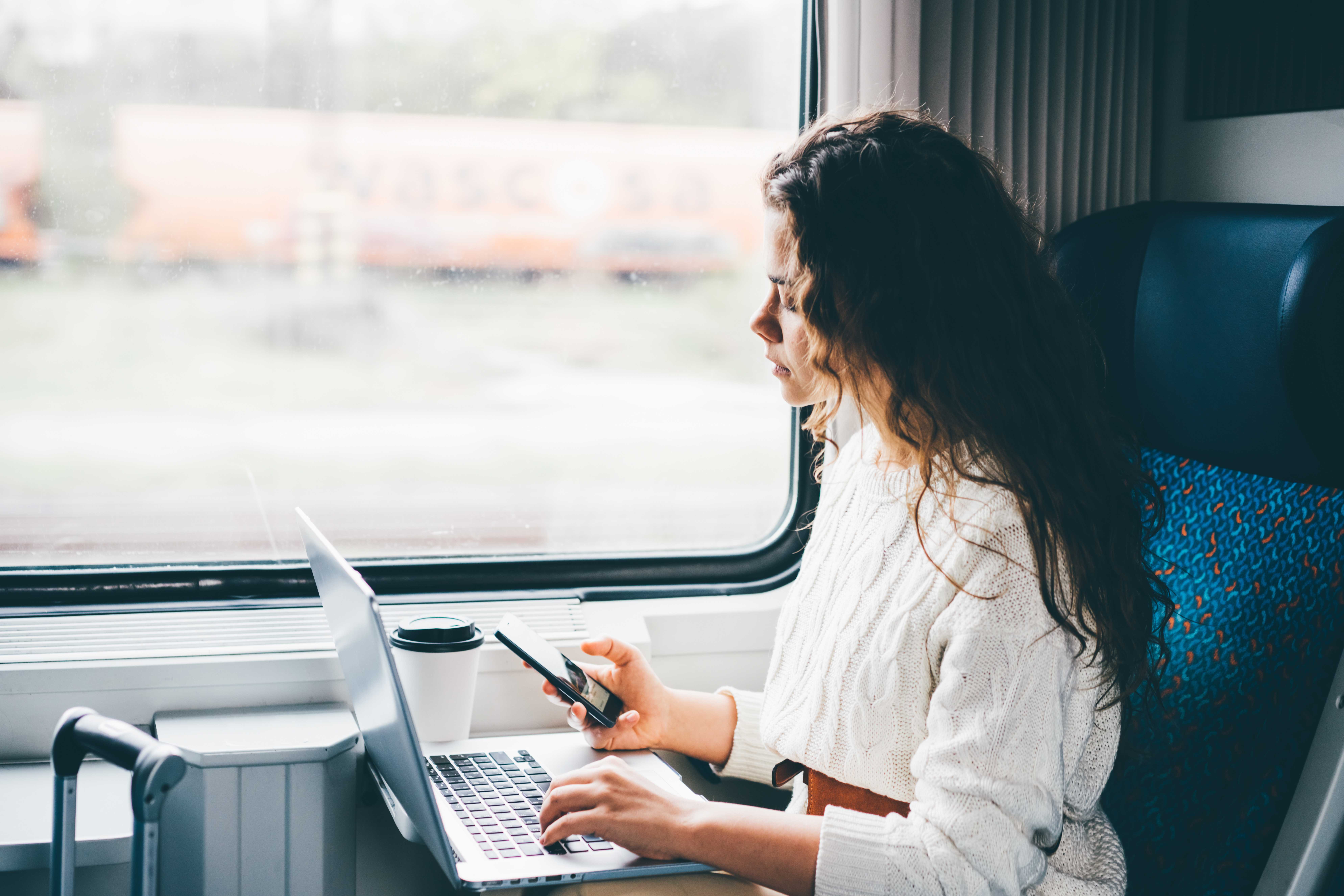 Small business owner commuting on a train with laptop