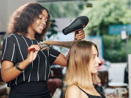 Hairdresser blow drying a clients hair in a hair salon