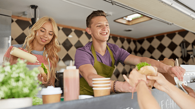 Two business owners serving food from a food truck