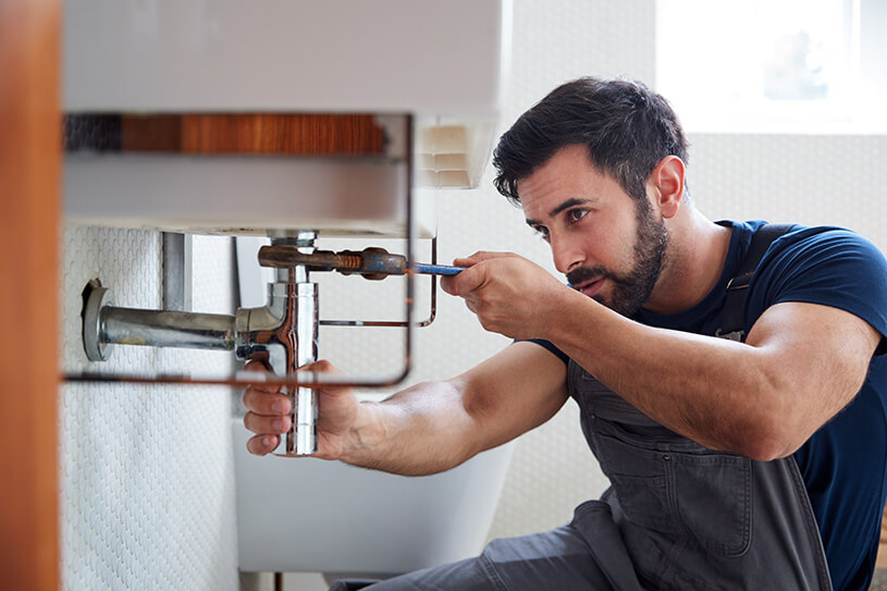 Plumber fixing broken sink in property