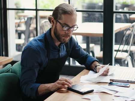 Man in glasses sitting at table and doing business calculations