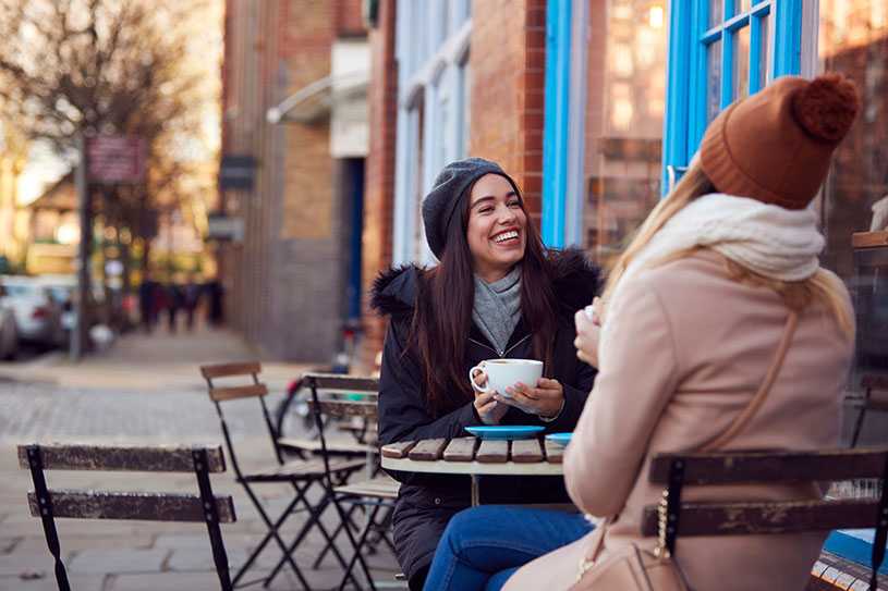 Two friends drinking coffee outside a cafe