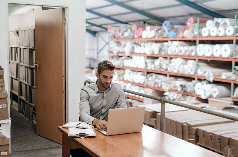 Business owner working on laptop in a warehouse