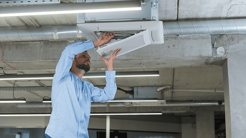 An engineer checking an air-conditioning ceiling unit