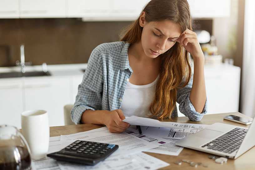 Concerned woman looking at bills with calculator