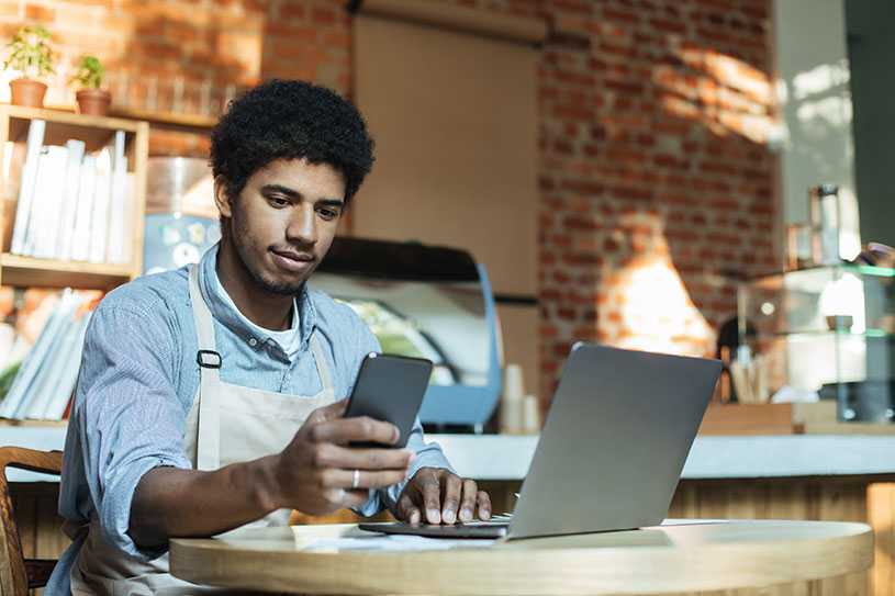 Man using phone and laptop in small business