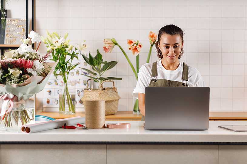 Florist managing online orders on laptop