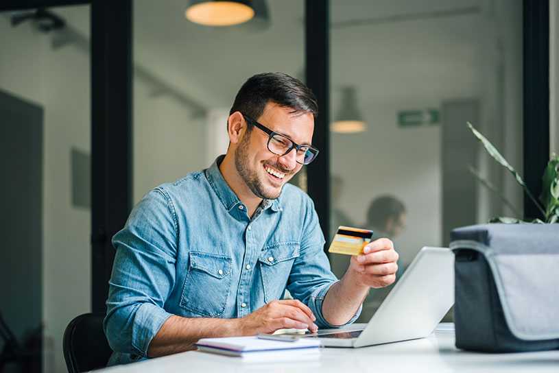 Smiling man using credit card to buy something online