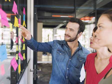 Business owners discussing strategy using sticky notes on a wall