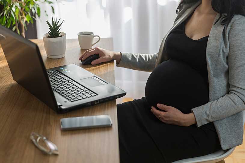 Pregnant woman working at a desk using a laptop