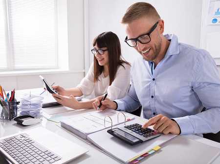 Business owners sat at a desk with calculator and records to calculate profit