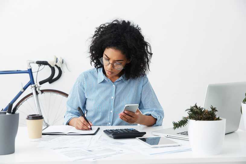 Businesswoman working on laptop with phone