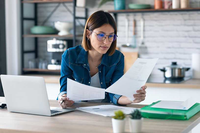 Woman with laptop looking at papers working from home
