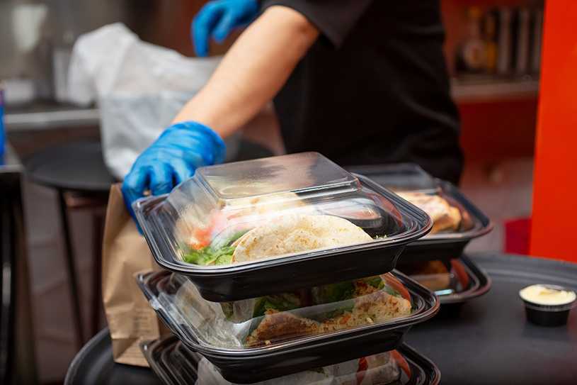 Restaurant owner preparing takeaway food in plastic containers
