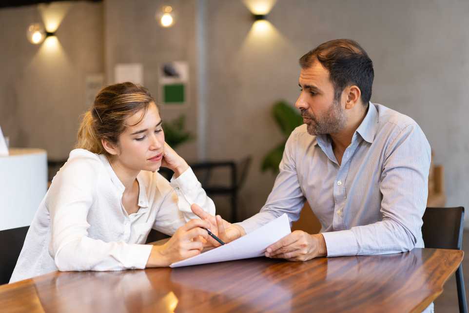 Two people discussing paperwork in an office
