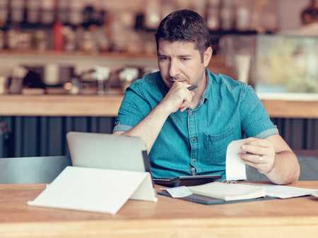 Man sat at a laptop calculating his business turnover