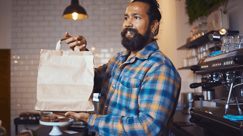 Male sales assistant holding a brown paper bag in a restaurant