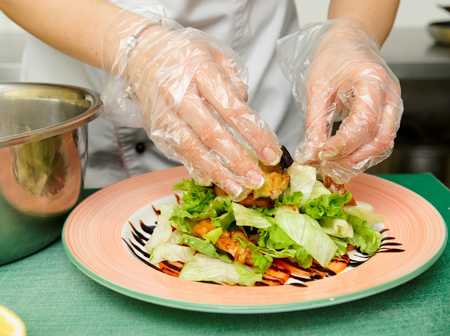 Chef preparing a salad while wearing gloves