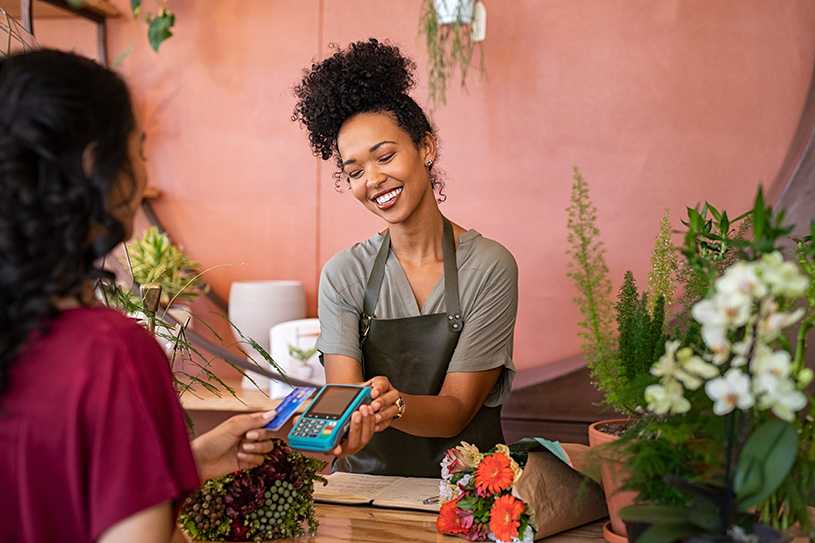 Smiling business owner and customer paying by card at flower shop