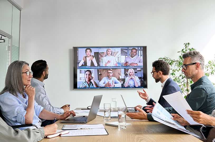 People in office with video conference screen on TV