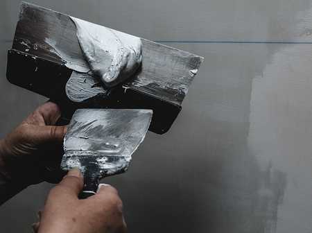 Tradesperson applying plaster to trowel