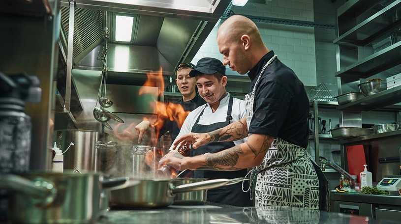 Three male chefs cooking in a restaurant kitchen 