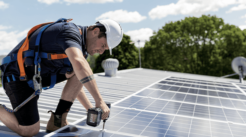 Workman fitting solar panels on a roof