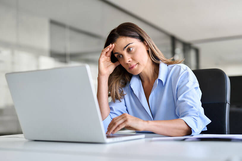 Female business owner looking stressed and worried at a laptop