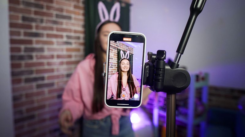 A girl wearing bunny ears films a TikTok from her mobile phone