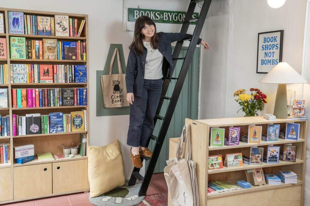 Jaimie inside her bookshop, Clemo Books, standing on a ladder
