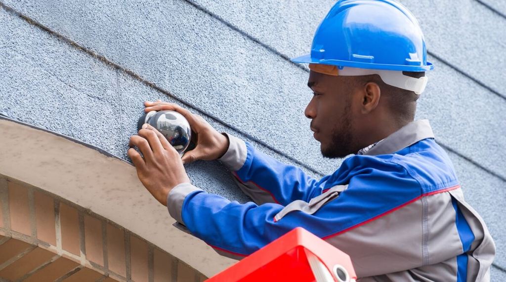 Man fitting a CCTV camera to a building