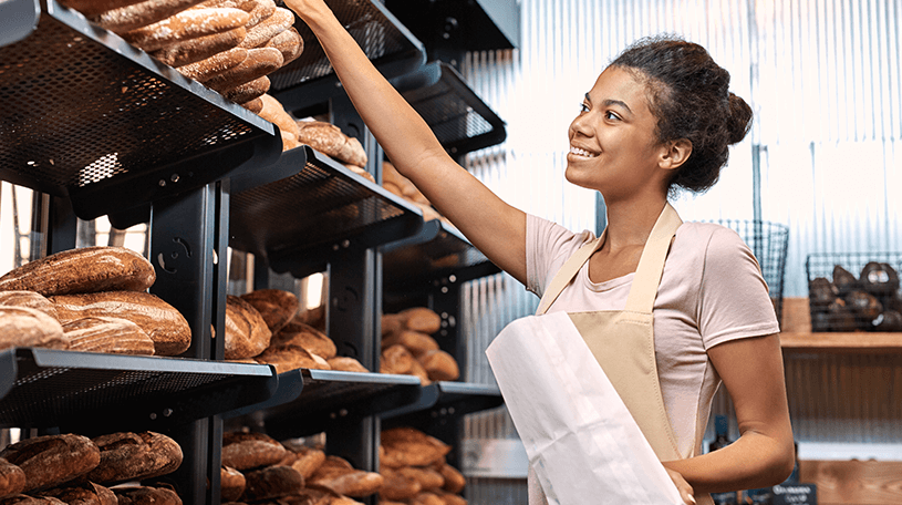 Baker putting bread on shelves