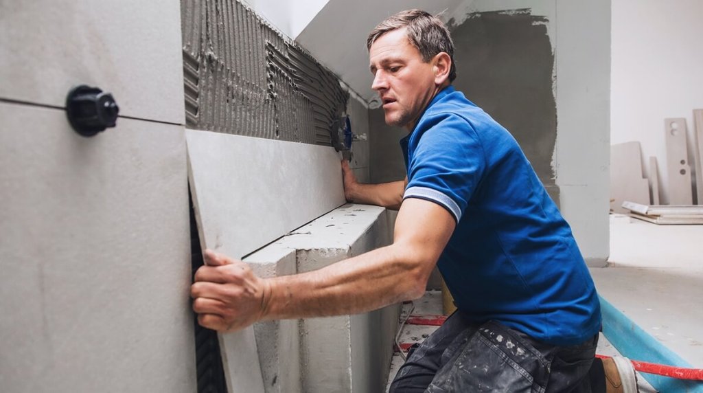 Bathroom fitter installing large grey bathroom wall tiles