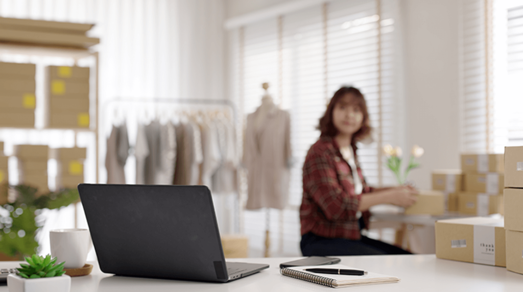 A laptop sat on a desk while business owner packs products