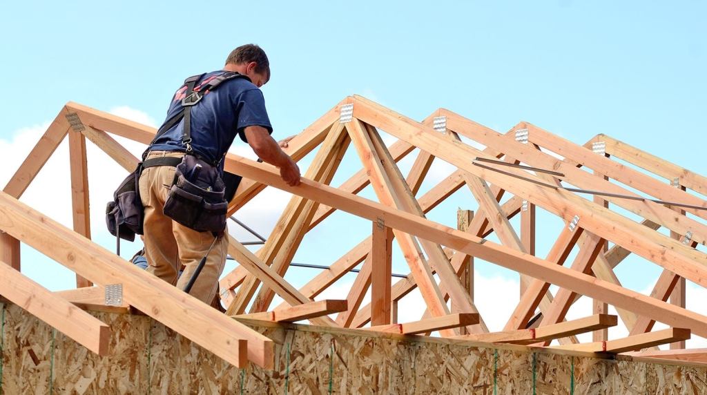 A carpenter installing roof trusses on a residential property
