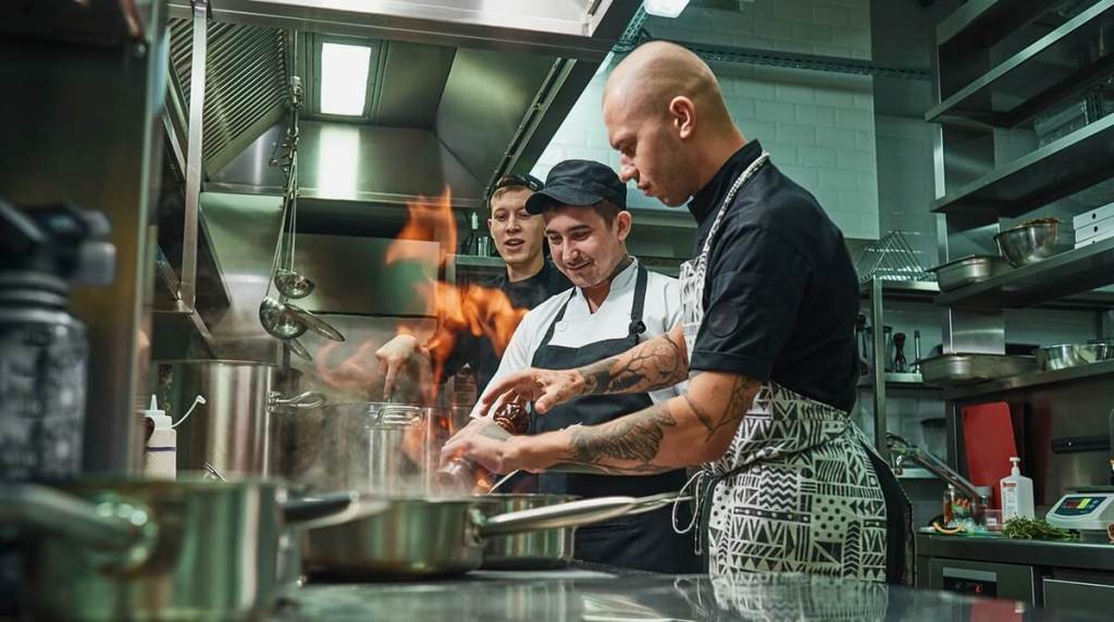 Three male chefs cooking in a restaurant kitchen