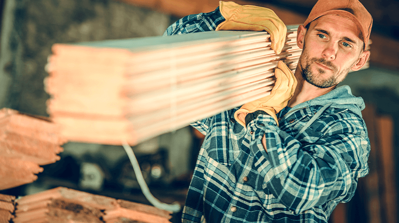 Workman carrying several planks of wood