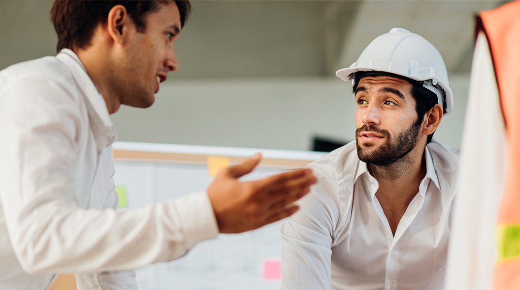 Two engineers discussing a project outside while wearing protecting clothing