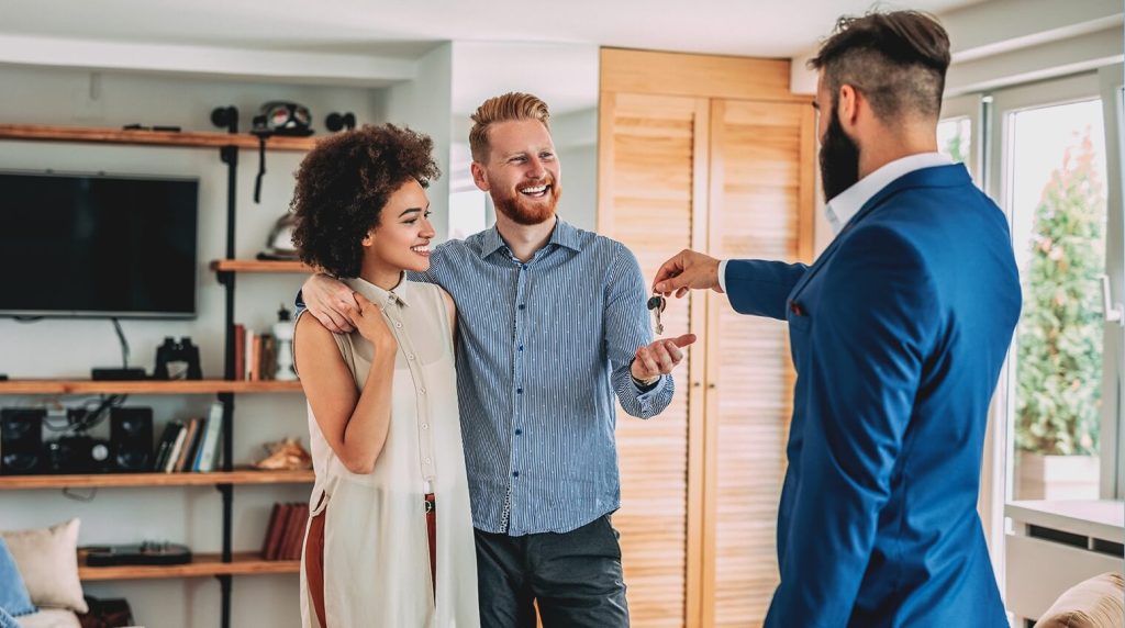 Estate agent handing over keys to couple  in their new home