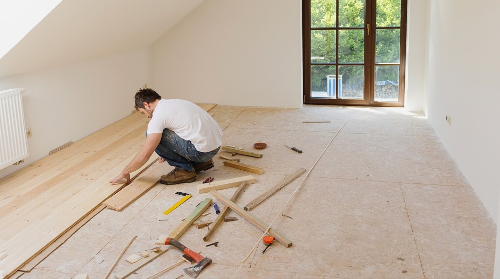 Flooring contractor installing wooden flooring in an attic conversion